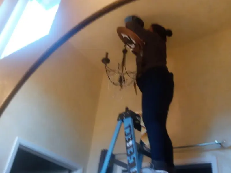 Electrician installing a chandelier in a Orange City residence